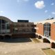 Red brick L-shaped building with archways and large glass windows