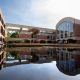 U-shaped moat filled with black water reflecting a red brick building with arched windows