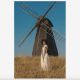 Woman wearing indigenous Nigerian clothing standing in front of a black windmill