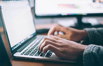 Photograph of hands typing on laptop keyboard