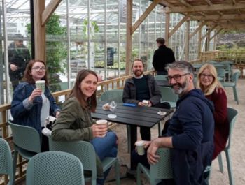 A photo of five colleagues from the School of Life Sciences around a table. Some have a cup of coffee or tea in their hands