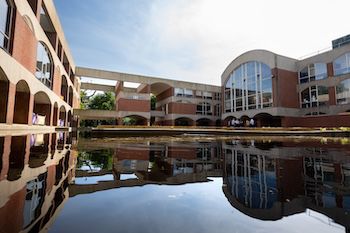 U-shaped moat filled with black water reflecting a red brick building with arched windows