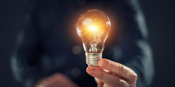 A hand holding a lighted lightbulb