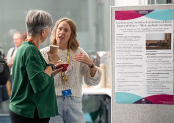 Two people stand in conversation at the 2025 Sussex Education Festival, in front of a research poster titled “Understanding the student experience of Black, Asian and Minority Ethnic students on campus.”